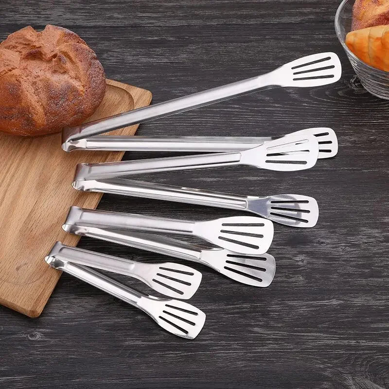 Set of stainless steel kitchen tongs on dark wood, plastic-free Stel cookware.